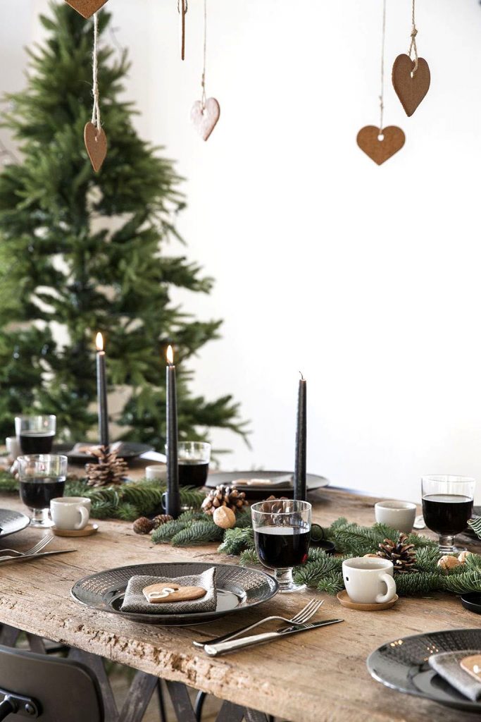 Bare Christmas tree behind a wooden table laid out with simple settings