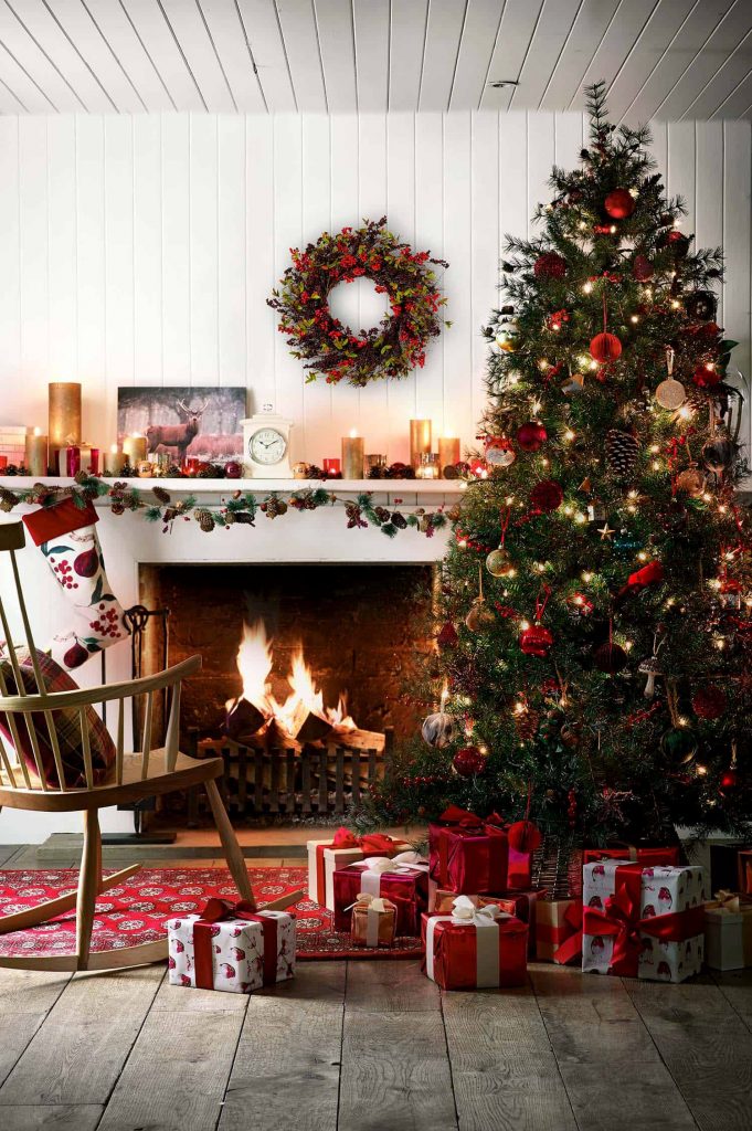 Christmas tree surrounded by presents by a light wood fire